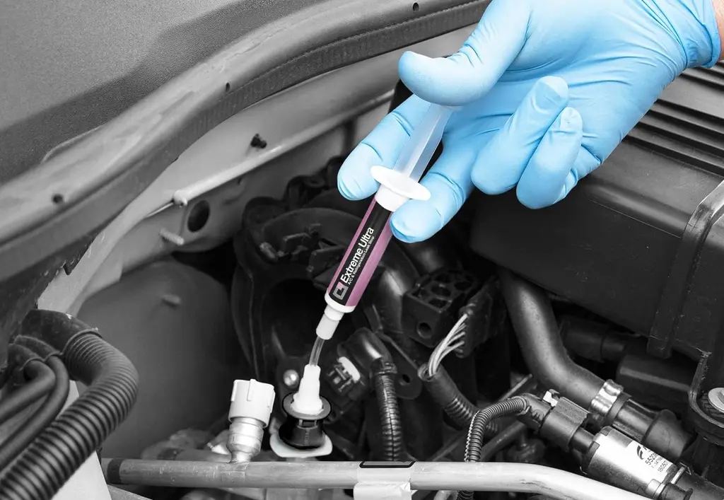 Main de mécanicien injectant un produit anti fuite de climatisation