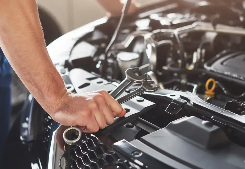 Main de mécanicien devant un moteur de voiture